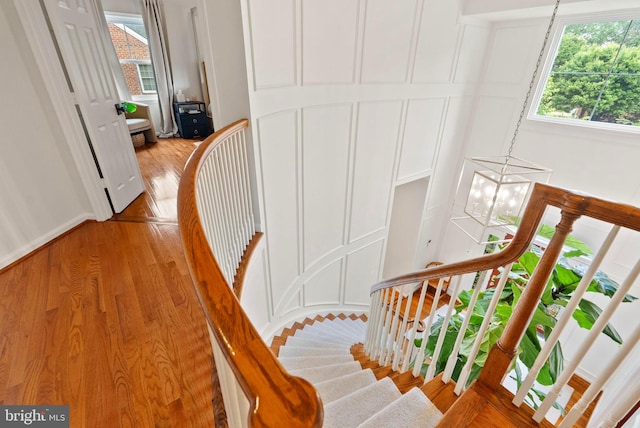 10000 Manor Pl, Fairfax, VA 22032 - staircase with a chandelier, a decorative wall, plenty of natural light, and wood finished floors