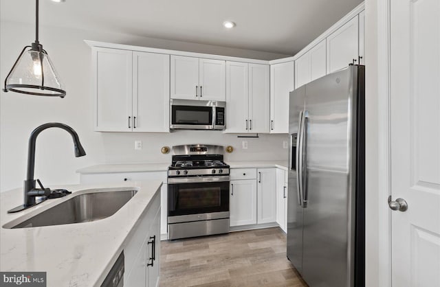 25040 Treeview Ln, Lewes, DE 19958 - kitchen with appliances with stainless steel finishes, a sink, white cabinets, light wood-type flooring, and recessed lighting
