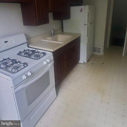 5016 Palmer Mill Rd, Clifton Heights, PA 19018 - kitchen featuring white range with gas cooktop, a sink, light floors, light countertops, and dark brown cabinets