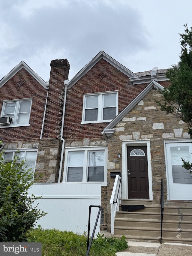 1727 Dallas St, Philadelphia, PA 19126 - view of property featuring stone siding, entry steps, a chimney, brick siding, and cooling unit