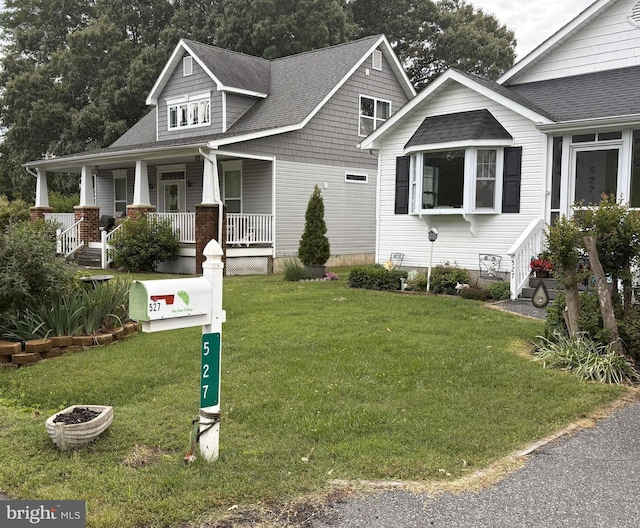 527 Monroe Bay Ave, Colonial Beach, VA 22443 - view of front of house with a front yard, covered porch, and a shingled roof