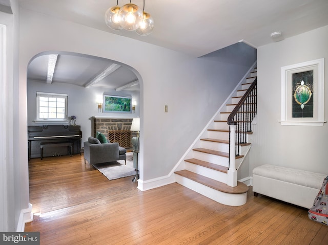1204 Drexel Ave, Drexel Hill, PA 19026 - stairs featuring arched walkways, hardwood / wood-style floors, a stone fireplace, and beam ceiling