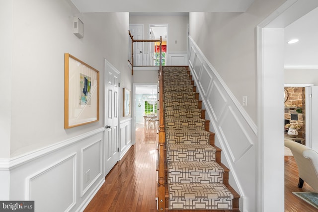 253 Lantern Ln, Gulph Mills, PA 19428 - staircase featuring a decorative wall, hardwood / wood-style flooring, a wainscoted wall, and a fireplace