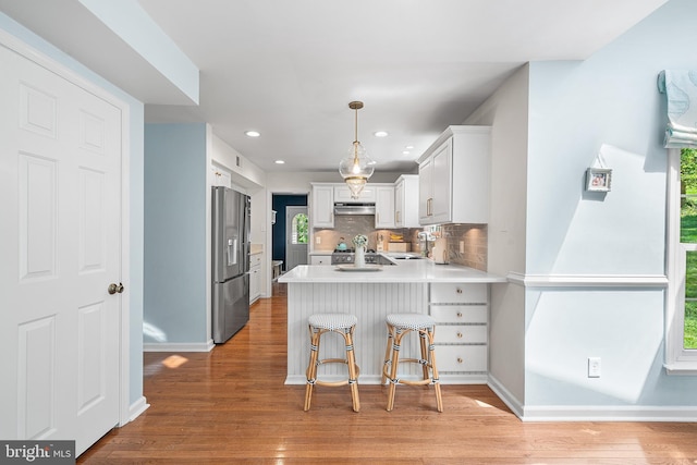 253 Lantern Ln, Gulph Mills, PA 19428 - kitchen with stainless steel refrigerator with ice dispenser, a peninsula, light wood finished floors, light countertops, and under cabinet range hood