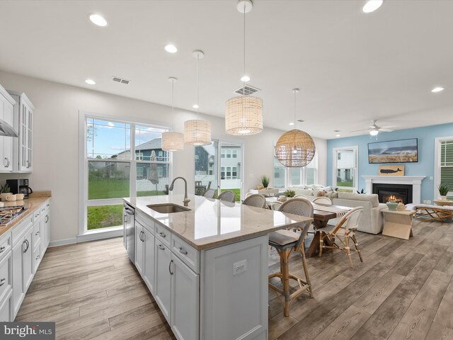 41 Beach Club Ave, Ocean View, DE 19970 - kitchen with a sink, a kitchen bar, light wood-style floors, ceiling fan, and a warm lit fireplace