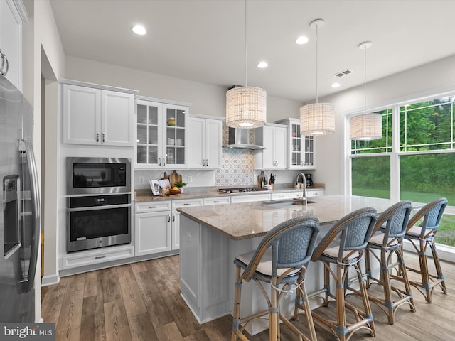 41 Beach Club Ave, Ocean View, DE 19970 - kitchen with stainless steel appliances, a sink, wall chimney range hood, light stone counters, and wood finished floors