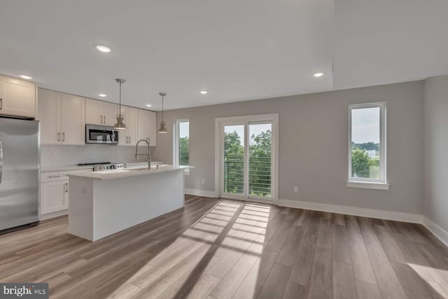 1947 N 33rd St, Philadelphia, PA 19121 - kitchen with appliances with stainless steel finishes, light countertops, baseboards, a kitchen island with sink, and tasteful backsplash