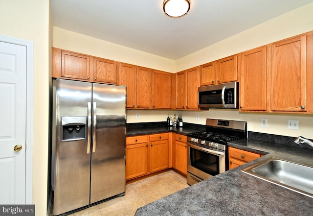 1664 Brynne Ln, Pottstown, PA 19464 - kitchen featuring appliances with stainless steel finishes, a sink, dark countertops, and brown cabinetry