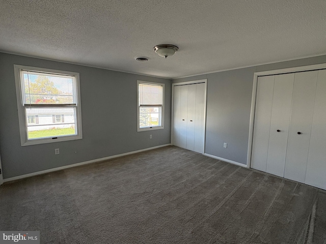 16 W Ninth St, Waynesboro, PA 17268 - unfurnished bedroom featuring two closets, a textured ceiling, baseboards, and dark carpet