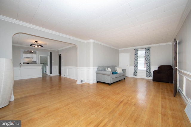 449 Audubon Ave, Audubon, NJ 08106 - living room with arched walkways, light wood-style flooring, crown molding, a decorative wall, and a wainscoted wall