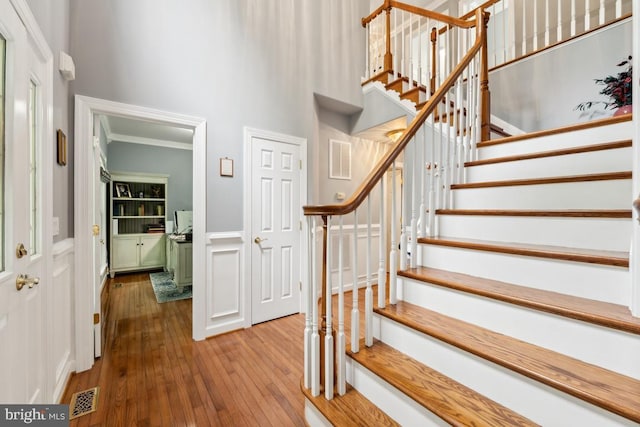 45 Saint Marys Ln, Stafford, VA 22556 - staircase with a towering ceiling, hardwood / wood-style flooring, a wainscoted wall, a decorative wall, and crown molding