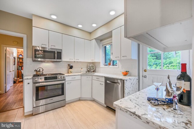 5408 Wehawken Rd, Bethesda, MD 20816 - kitchen featuring stainless steel appliances, white cabinets, backsplash, light wood-style floors, and recessed lighting