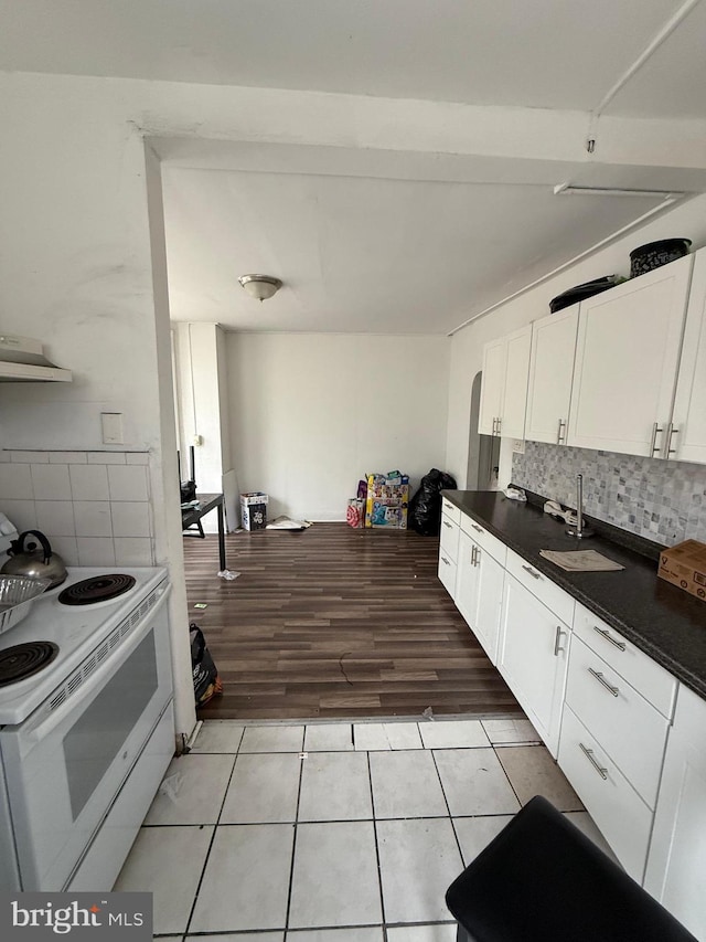 1512 Lindley Ave, Philadelphia, PA 19141 - kitchen featuring white electric stove, dark countertops, white cabinetry, range hood, and light tile patterned flooring