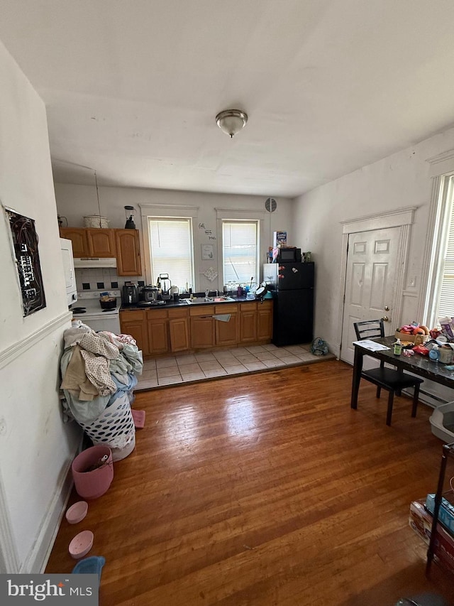 1512 Lindley Ave, Philadelphia, PA 19141 - kitchen with freestanding refrigerator, light wood-style floors, white range with electric cooktop, brown cabinetry, and under cabinet range hood