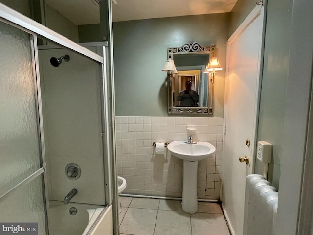 102 N 11th St, Reading, PA 19601 - bathroom with radiator, tile patterned floors, tile walls, toilet, and combined bath / shower with glass door
