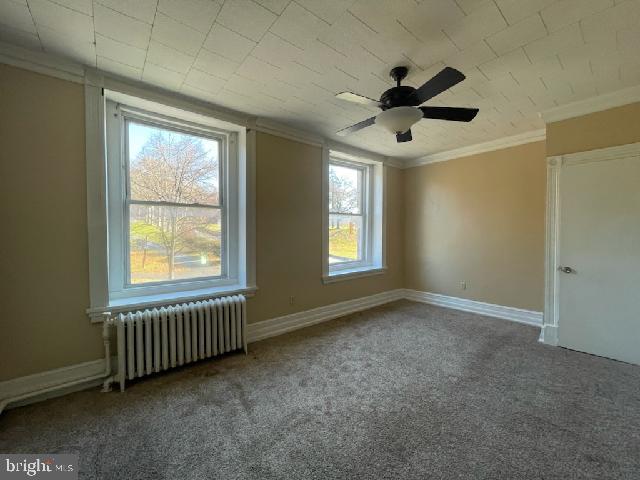 102 N 11th St, Reading, PA 19601 - carpeted spare room with radiator, ornamental molding, a ceiling fan, and baseboards