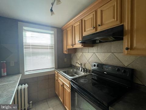 102 N 11th St, Reading, PA 19601 - kitchen featuring electric range, under cabinet range hood, radiator, a sink, and light tile patterned floors