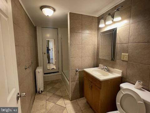 102 N 11th St, Reading, PA 19601 - bathroom with radiator, toilet, vanity, tile walls, and tile patterned floors