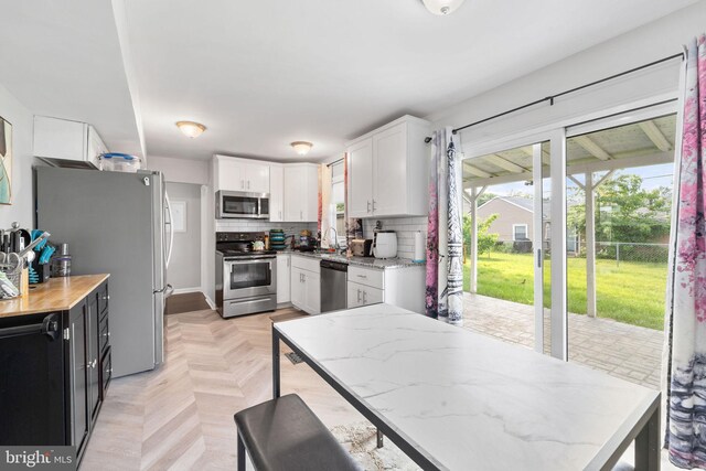 35 Mullshire Ln, Willingboro, NJ 08046 - kitchen with stainless steel appliances, a sink, white cabinets, light stone countertops, and decorative backsplash