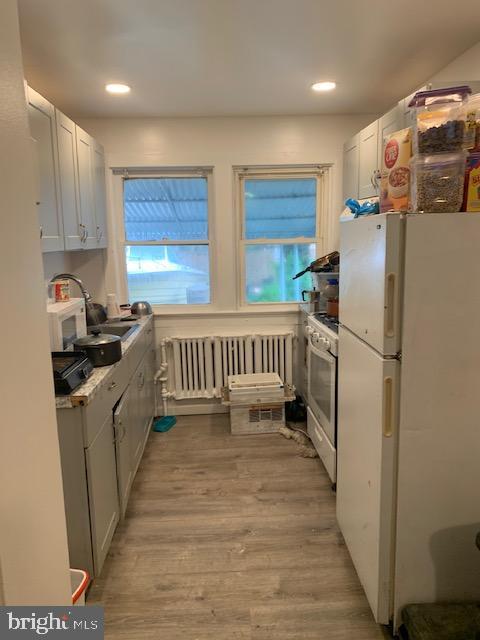 812 Tulip St, Camden, NJ 08104 - kitchen with white appliances, radiator, light wood-style flooring, recessed lighting, and a sink