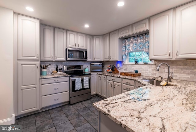 167 Windmill Rd, Willow Grove, PA 19090 - kitchen featuring appliances with stainless steel finishes, a sink, light stone counters, tasteful backsplash, and dark tile patterned flooring