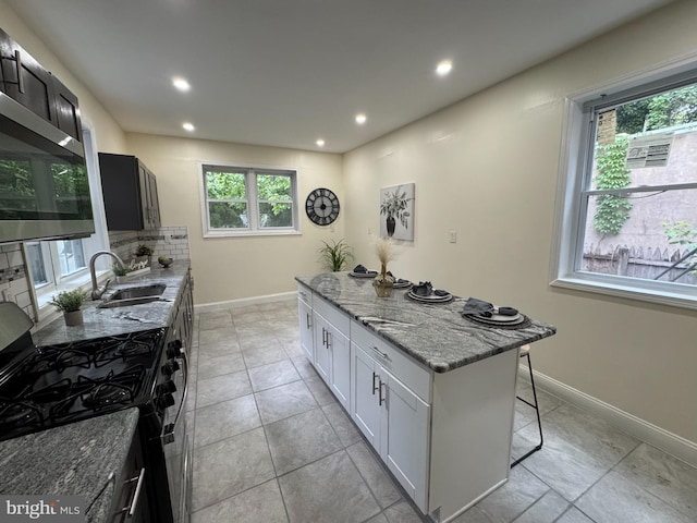 2411 N W St, Wilmington, DE 19802 - kitchen with stainless steel appliances, a sink, a kitchen island, light stone countertops, and healthy amount of natural light