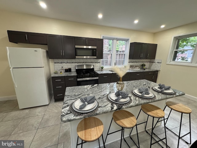 2411 N W St, Wilmington, DE 19802 - kitchen featuring appliances with stainless steel finishes, light stone countertops, decorative backsplash, baseboards, and a kitchen bar
