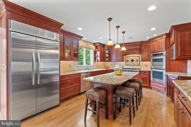 25 Ginnie Ln, West Windsor, NJ 08550 - kitchen with built in appliances, light wood-style floors, hanging light fixtures, glass insert cabinets, and a kitchen bar