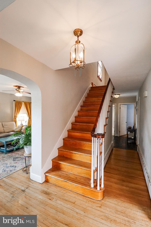 72 Springs Ave, Gettysburg, PA 17325 - stairs with hardwood / wood-style flooring, a baseboard heating unit, arched walkways, baseboards, and a baseboard radiator