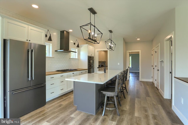 104 Lightfoot Ln, Dillsburg, PA 17019 - kitchen with stainless steel appliances, wall chimney range hood, white cabinets, wood finished floors, and tasteful backsplash