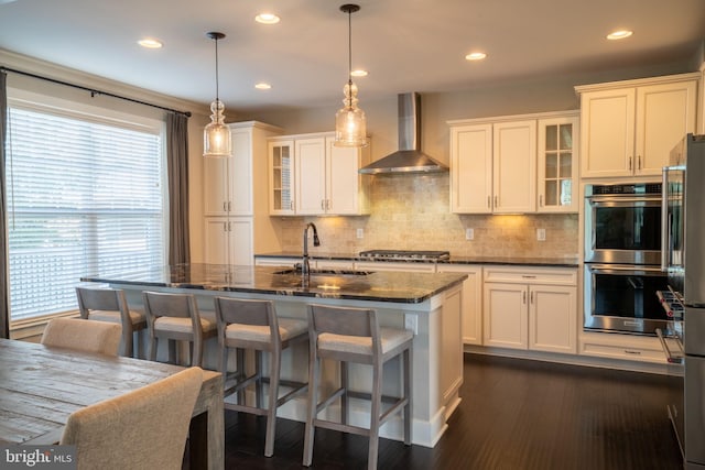 22270 Foggy Ridge Ter, Ashburn, VA 20148 - kitchen featuring wall chimney range hood, appliances with stainless steel finishes, a sink, backsplash, and dark stone countertops