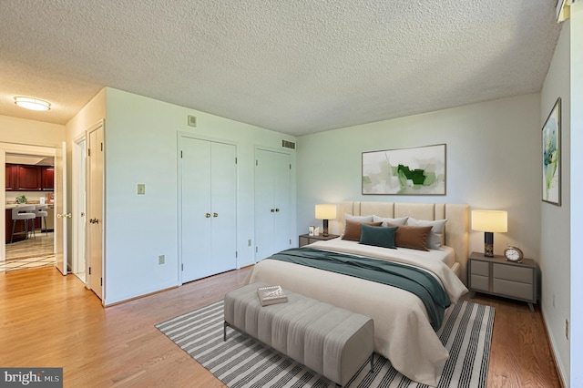 1101 S Arlington Ridge Rd Unit 216, Arlington, VA 22202 - bedroom with light wood-type flooring, a textured ceiling, baseboards, and multiple closets