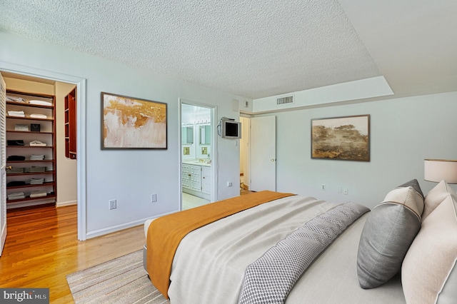 1101 S Arlington Ridge Rd Unit 216, Arlington, VA 22202 - bedroom featuring light wood-style flooring, a walk in closet, a textured ceiling, a closet, and baseboards