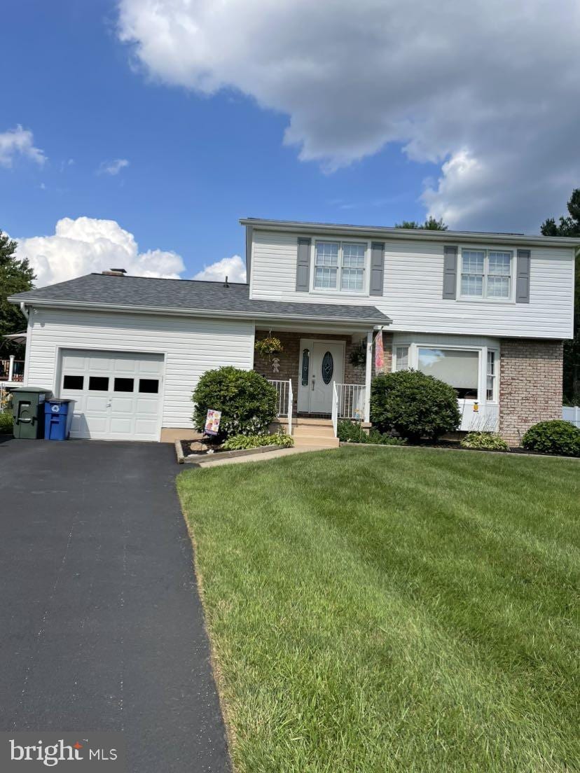 2419 Plainhurst Way, Reisterstown, MD 21136 - view of front facade featuring a garage, a porch, a front yard, asphalt driveway, and brick siding