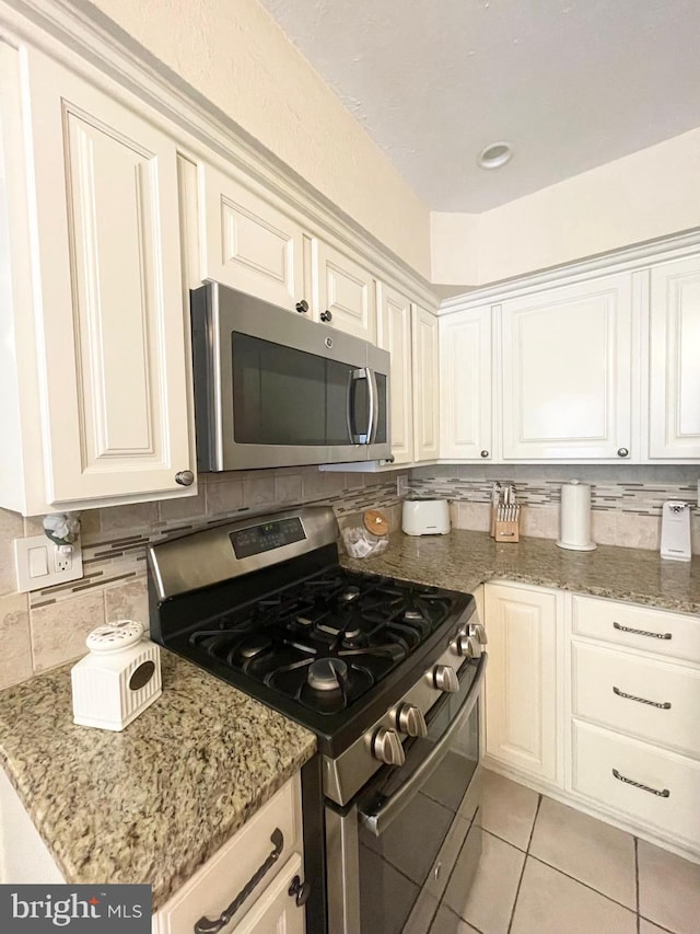 1820 S Dover St, Philadelphia, PA 19145 - kitchen featuring stainless steel appliances, decorative backsplash, light tile patterned flooring, and light stone countertops