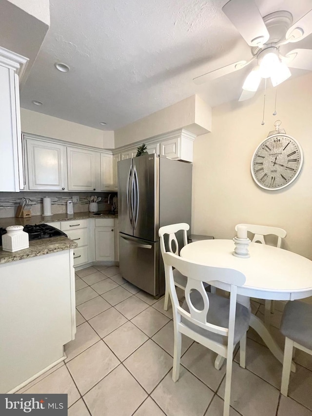 1820 S Dover St, Philadelphia, PA 19145 - kitchen with freestanding refrigerator, white cabinets, light tile patterned floors, stovetop, and a ceiling fan