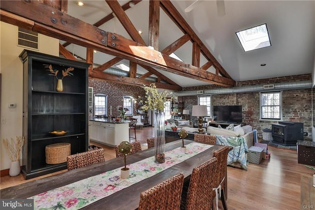 517 W Burke St, Easton, PA 18042 - dining room featuring a skylight, a wood stove, brick wall, light wood-type flooring, and beamed ceiling