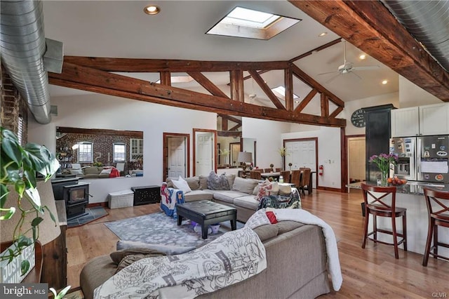 517 W Burke St, Easton, PA 18042 - living room featuring a wood stove, a skylight, light wood-style flooring, beamed ceiling, and ceiling fan