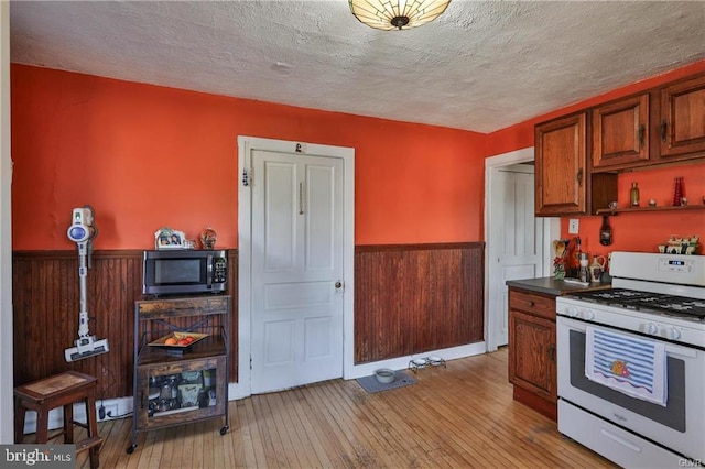 517 W Burke St, Easton, PA 18042 - kitchen featuring white gas stove, a wainscoted wall, a textured ceiling, light wood-style floors, and wooden walls