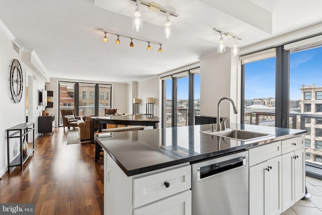 616 E St NW Unit 1114, Washington, DC 20004 - kitchen with stainless steel dishwasher, a sink, dark countertops, open floor plan, and a center island with sink