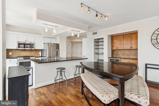 616 E St NW Unit 1114, Washington, DC 20004 - kitchen featuring stainless steel appliances, rail lighting, dark countertops, a sink, and crown molding