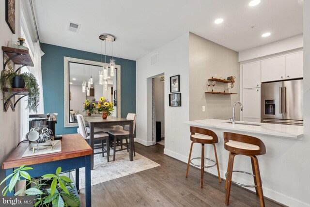 625 Slaters Ln Unit 201, Alexandria, VA 22314 - kitchen featuring high end refrigerator, a sink, dark wood-style flooring, white cabinetry, and light countertops