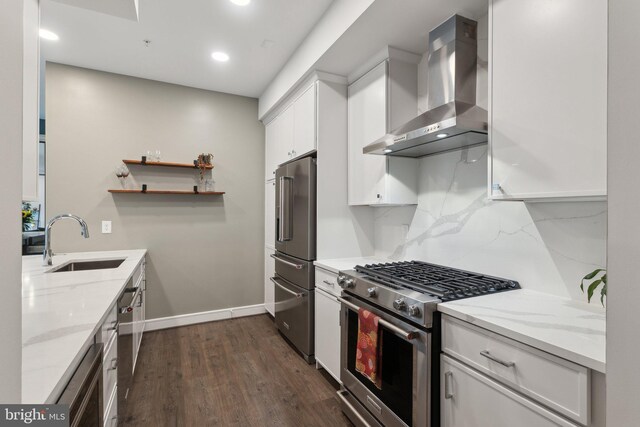 625 Slaters Ln Unit 201, Alexandria, VA 22314 - kitchen featuring premium appliances, wall chimney range hood, a sink, white cabinets, and baseboards