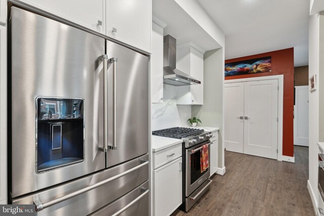 625 Slaters Ln Unit 201, Alexandria, VA 22314 - kitchen featuring high end appliances, wall chimney range hood, white cabinetry, light countertops, and wood finished floors