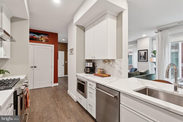 625 Slaters Ln Unit 201, Alexandria, VA 22314 - kitchen featuring stainless steel appliances, a sink, light wood finished floors, white cabinetry, and recessed lighting