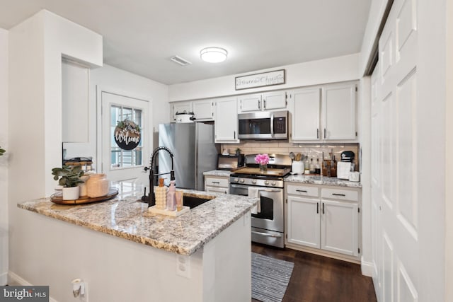 603 Lindsley Ct, Burlington, NJ 08016 - kitchen with stainless steel appliances, a sink, a peninsula, decorative backsplash, and light stone counters