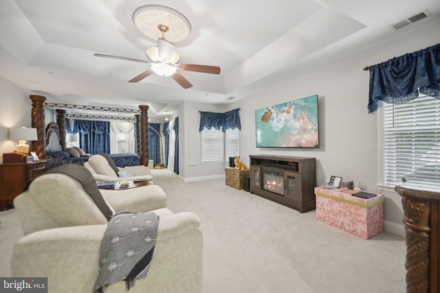 14201 Village Manor Ct, Upper Marlboro, MD 20774 - living area featuring a tray ceiling, a glass covered fireplace, a ceiling fan, baseboards, and carpet flooring