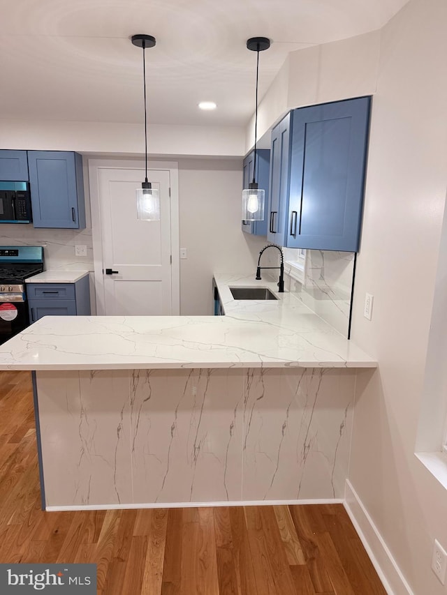 114 Marshall Rd, Lansdowne, PA 19050 - kitchen with black microwave, stainless steel range with gas stovetop, a sink, a peninsula, and wood finished floors