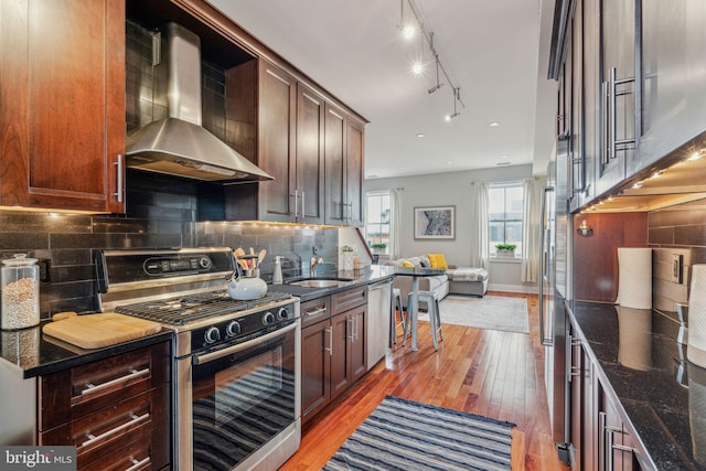 2031 Pine St Unit 4, Philadelphia, PA 19103 - kitchen with appliances with stainless steel finishes, wall chimney exhaust hood, light wood finished floors, dark stone counters, and a sink