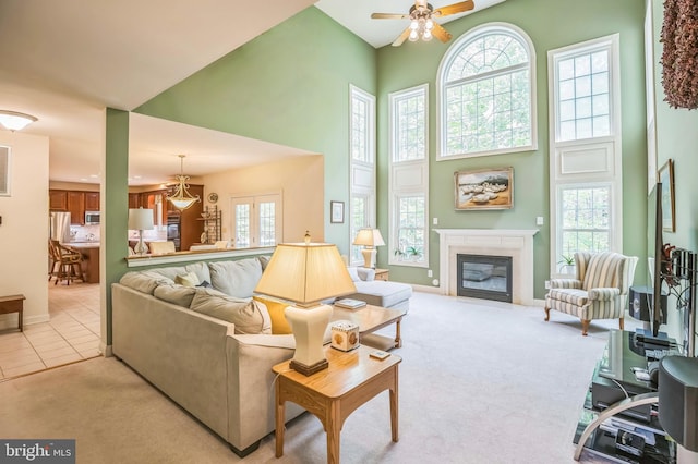 40801 Kiskadee Ln, Leonardtown, MD 20650 - living room featuring a towering ceiling, a ceiling fan, healthy amount of natural light, a glass covered fireplace, and light colored carpet
